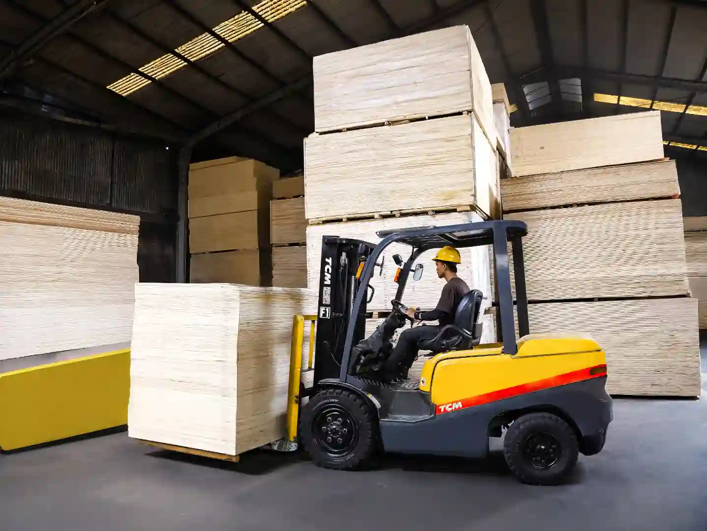 Forklift mengangkat plywood di gudang Hojaya