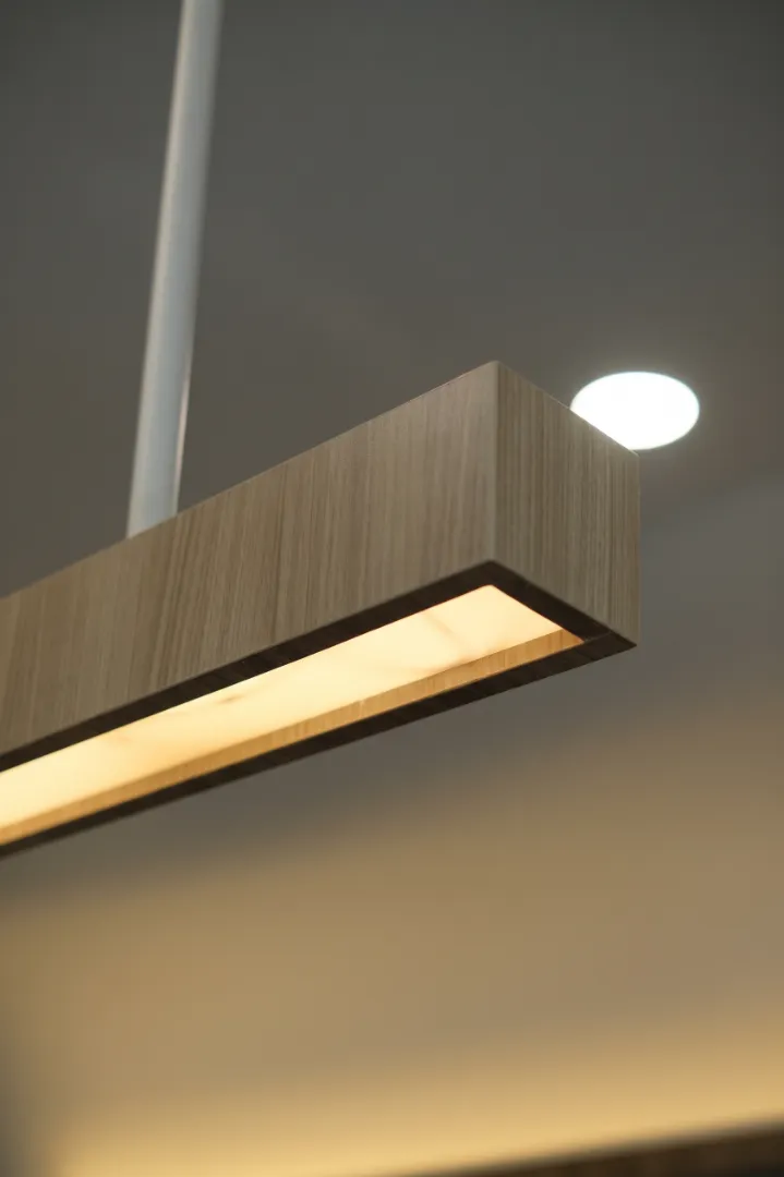 Close-up tepi rumah lampu gantung yang dibungkus HPL woodgrain, sambungan rapat tanpa celah